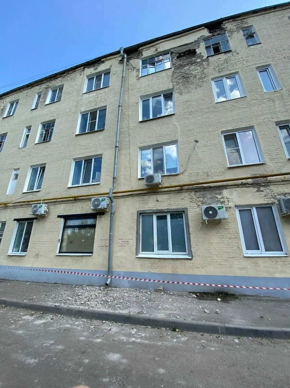 Куски бетона падают у входа во двор: УК ограничила доступ лентой, но проход под обломками остаётся единственным сухим маршрутом во время дождя.